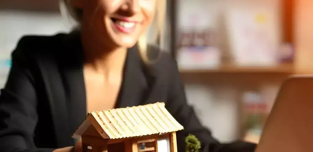 small house in the foresight, with a business woman using a laptop in the background.